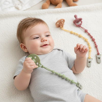 attache tetine main bebe souriant dos