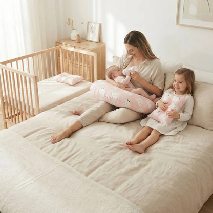 Bébé  boit son biberon sur coussin d' allaitement rose