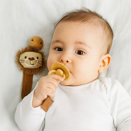 bebe calme prend tétine avec sa main et attache tetine