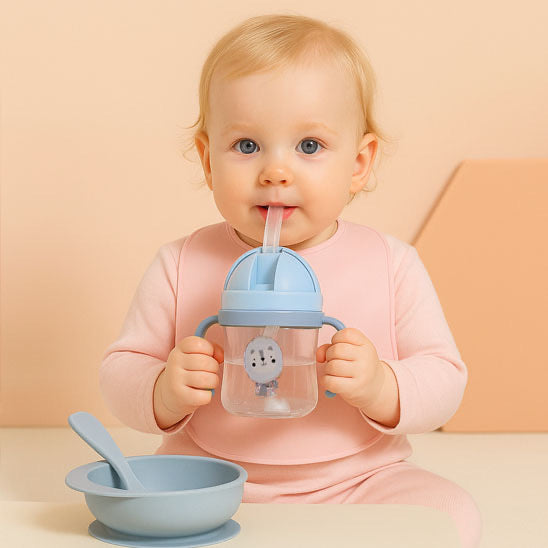 bébé fille boit avec un verre pour bébé bleu