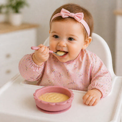 Bébé mange avec assiette bébé rose