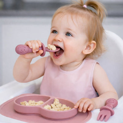 Bébé mange avec couvert bébé rose
