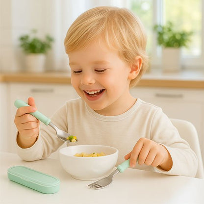 Bébé mange avec couverts bébé​ en souriant 