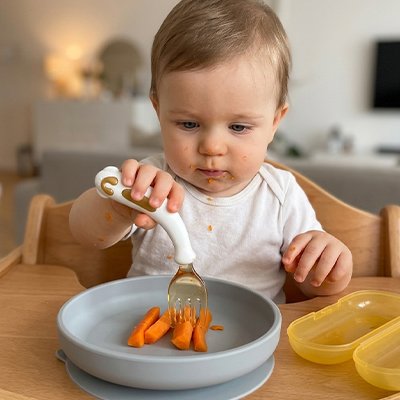 Bébé mange avec un couvert pour bébé ​