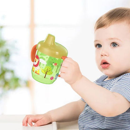 bébé prend un gobelet bébé vert avec sa main