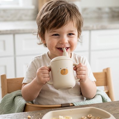 Gobelet pour bébé beige dans les mains du bébé