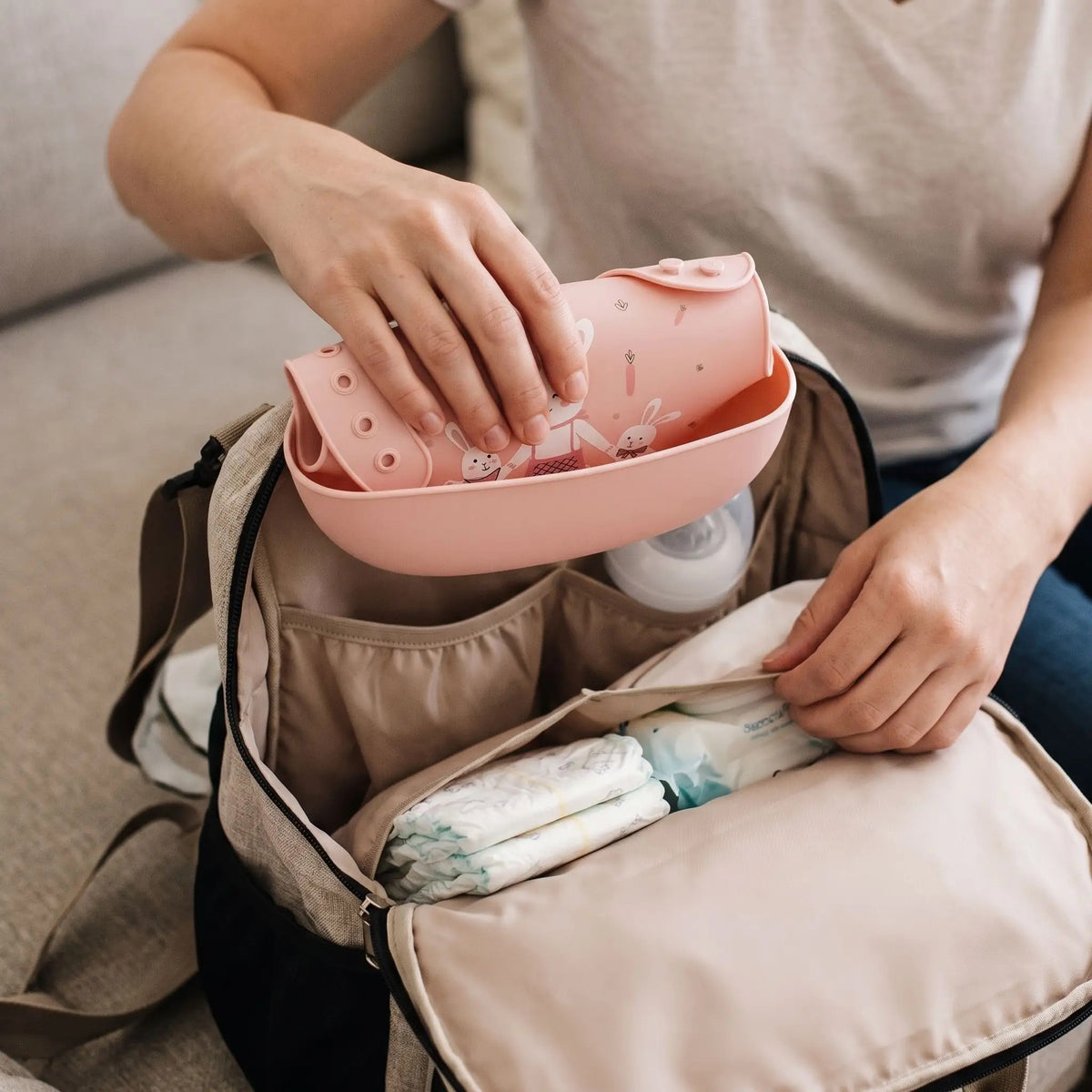maman met un bavoir récupérateur avec motif lapin rose dans un sac a langer