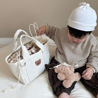 Sac à langer beige à côté du  bébé 