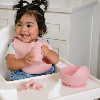 Une assiette bébé rose sur la chaise haute