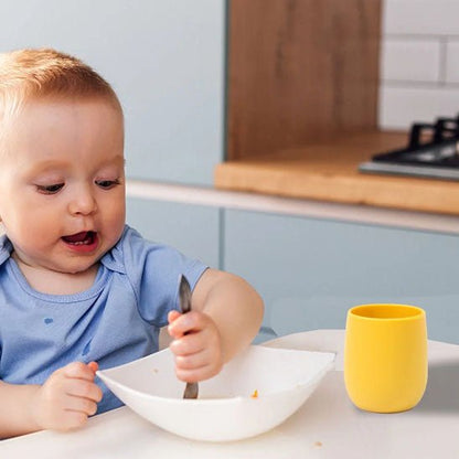 verre bébé jaune sur table avec bébé qui mange