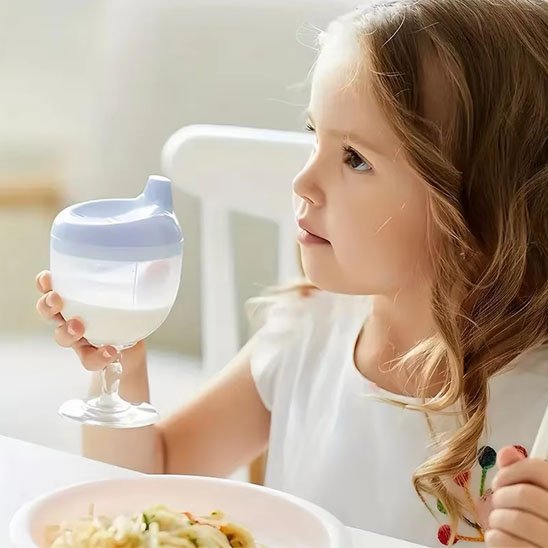 verre pour bébé violet dans les mains d'une fille 